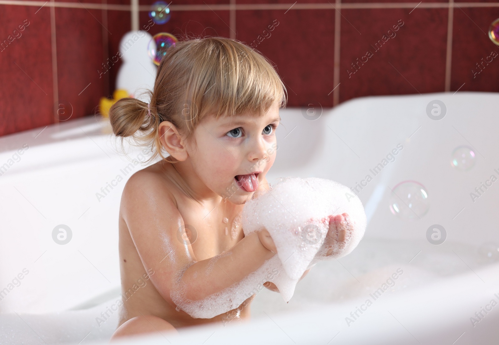 Photo of Little girl having fun in bathtub at home