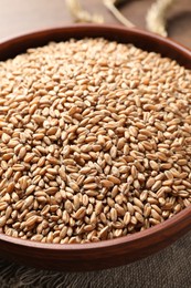 Bowl full of wheat grains on table, closeup