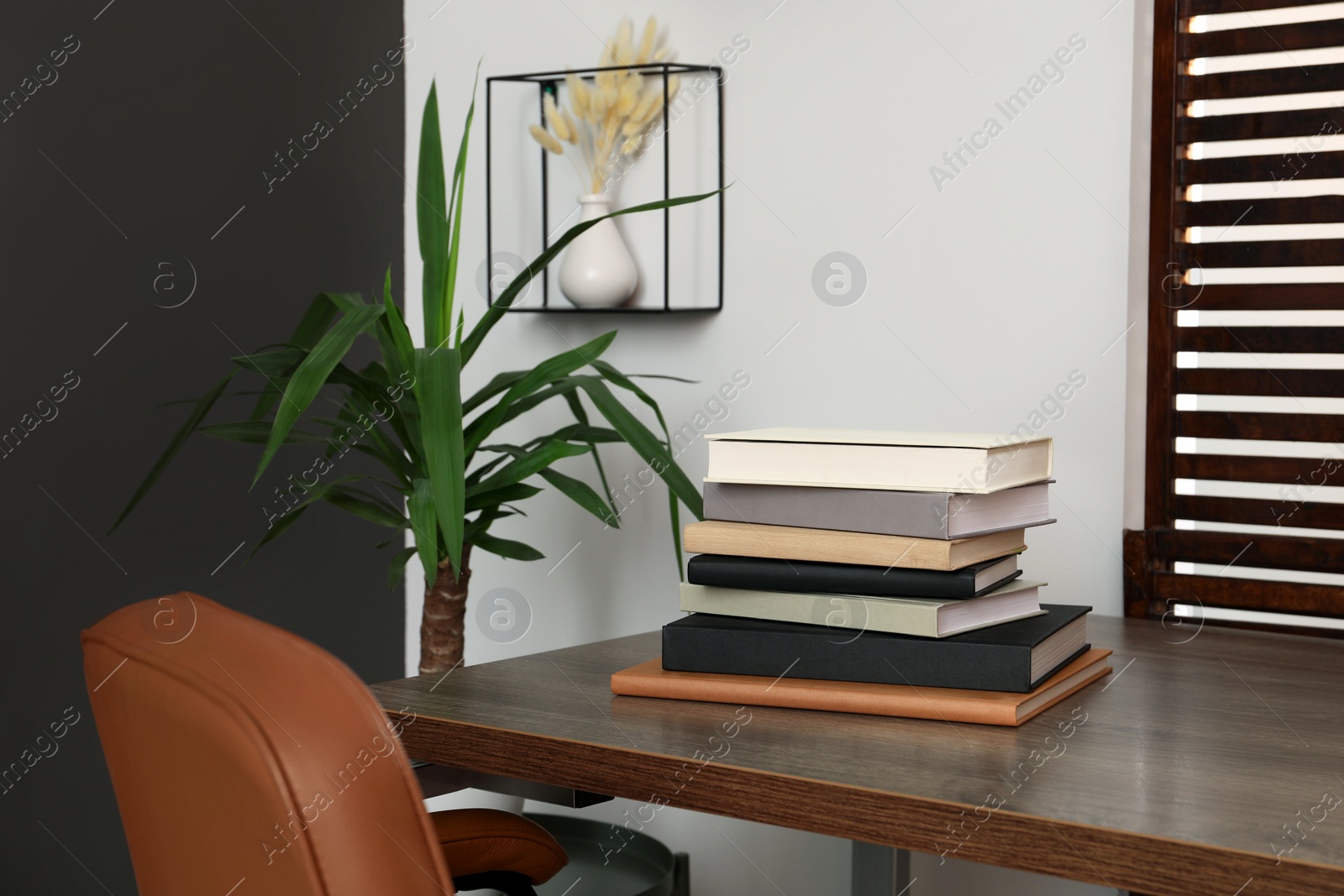 Photo of Stack of different hardcover books on wooden table indoors