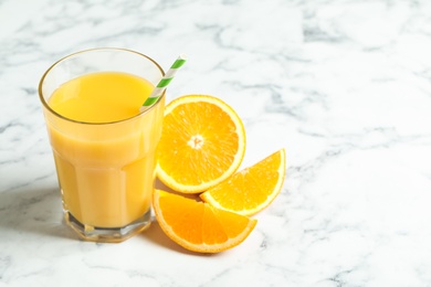 Photo of Glass of orange juice and fresh fruits on white marble table