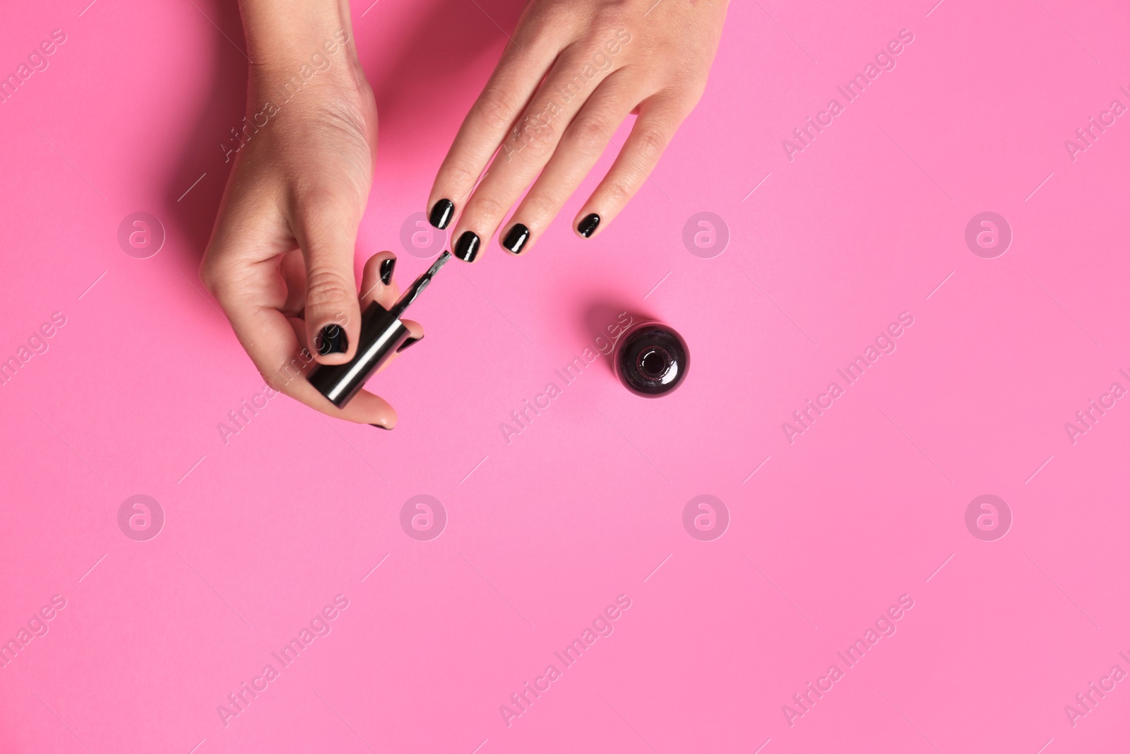 Photo of Woman applying nail polish on color background, top view with space for text
