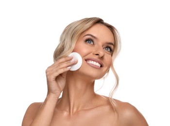 Smiling woman removing makeup with cotton pad on white background