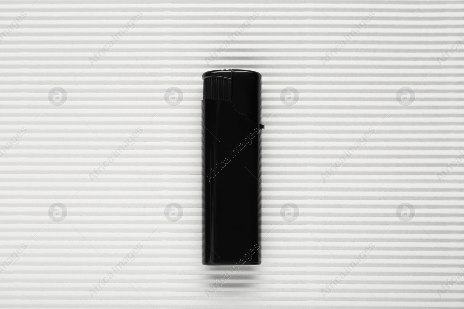 Photo of Stylish small pocket lighter on white corrugated fiberboard, top view