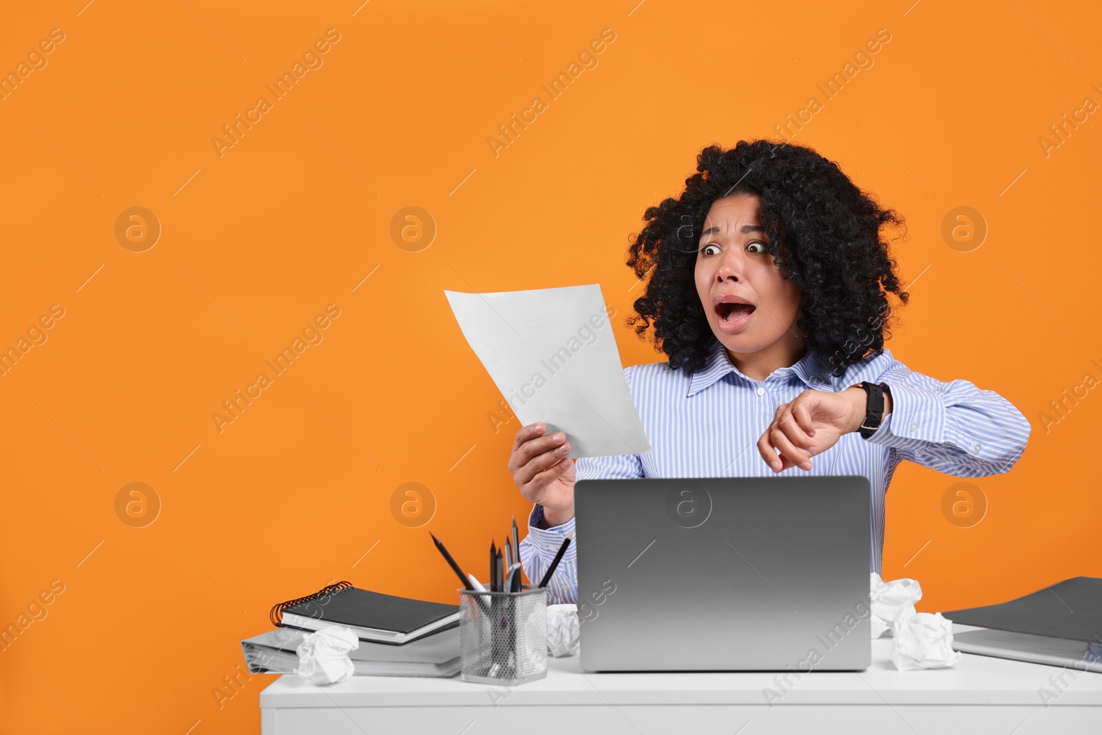 Photo of Stressful deadline. Scared woman looking at document at white desk against orange background. Space for text