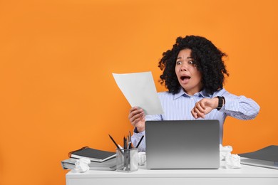 Stressful deadline. Scared woman looking at document at white desk against orange background. Space for text