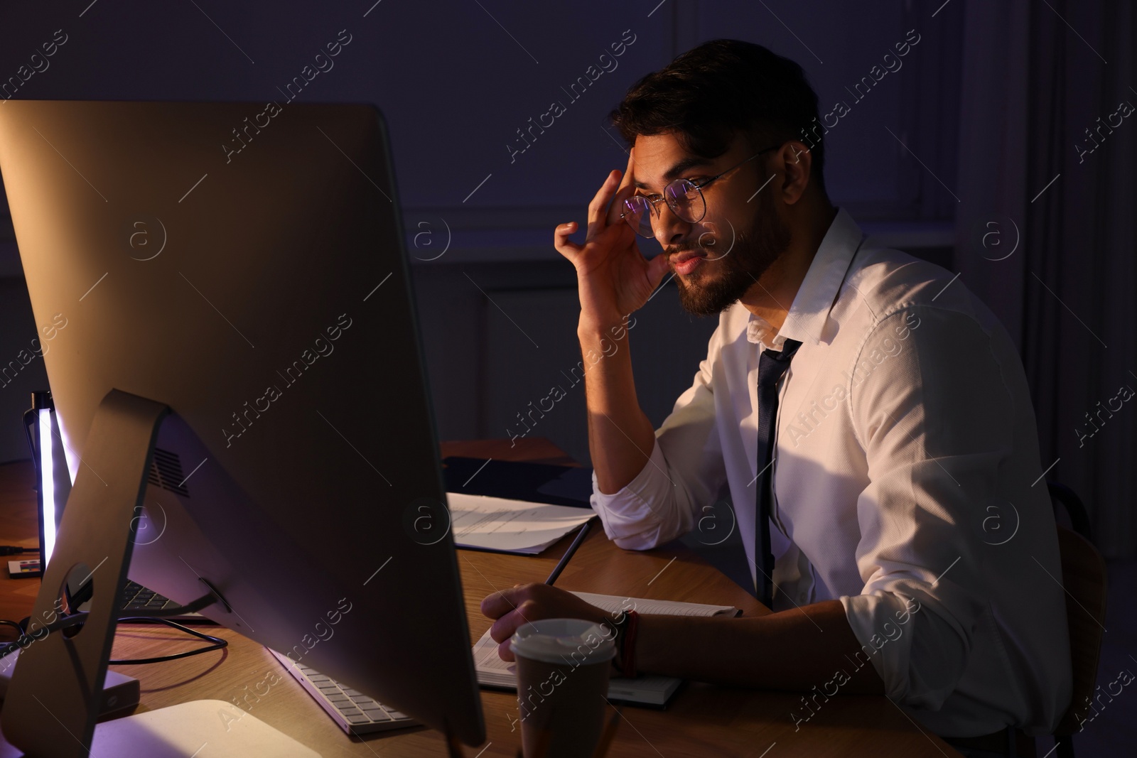 Photo of Tired young man working late in office