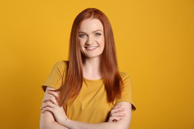 Photo of Candid portrait of happy young woman with charming smile and gorgeous red hair on yellow background