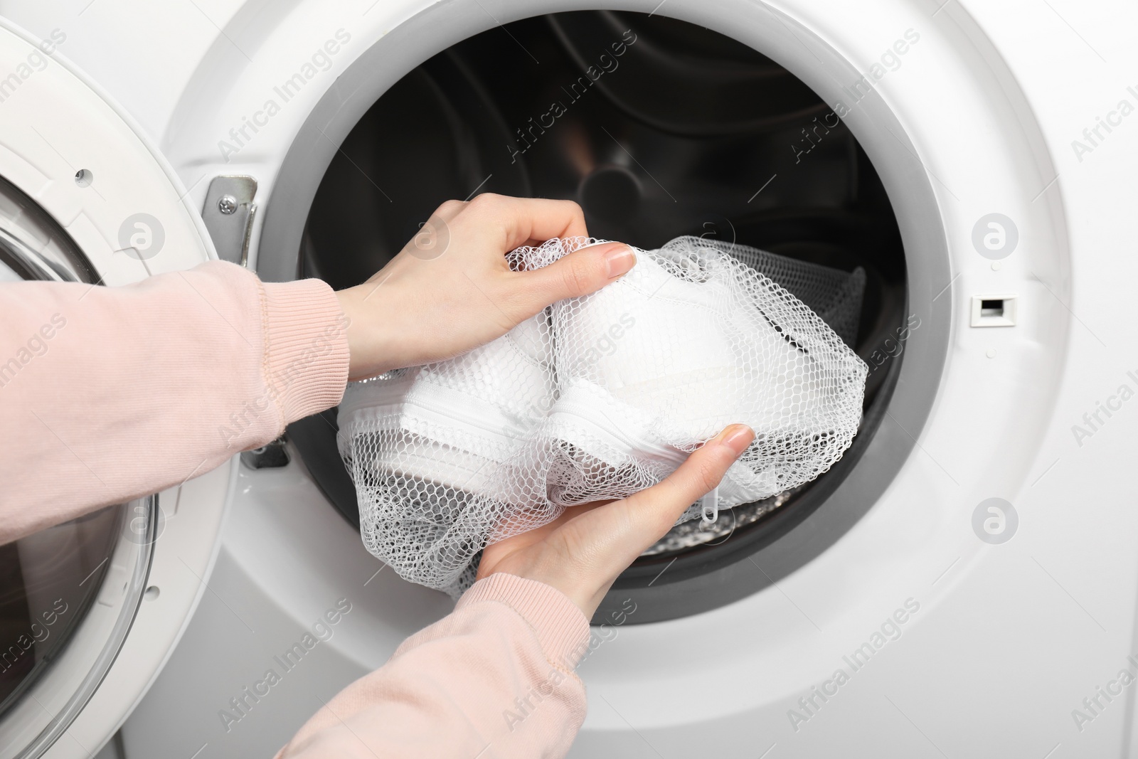 Photo of Woman putting stylish sneakers into washing machine, closeup