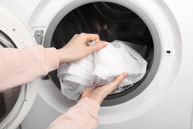 Photo of Woman putting stylish sneakers into washing machine, closeup