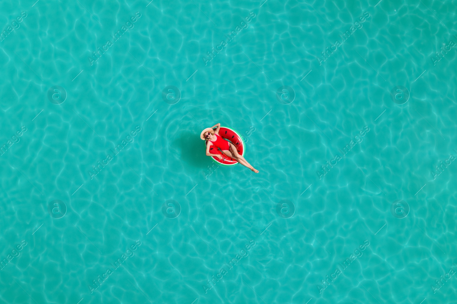 Image of Young happy woman with inflatable ring in swimming pool, top view. Summer vacation