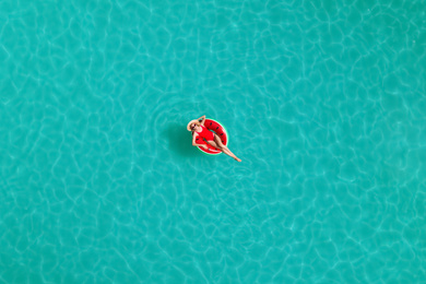 Image of Young happy woman with inflatable ring in swimming pool, top view. Summer vacation