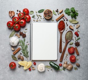 Open recipe book and different ingredients on grey table, flat lay. Space for text