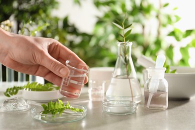 Photo of Scientist making cosmetic product at grey table, closeup