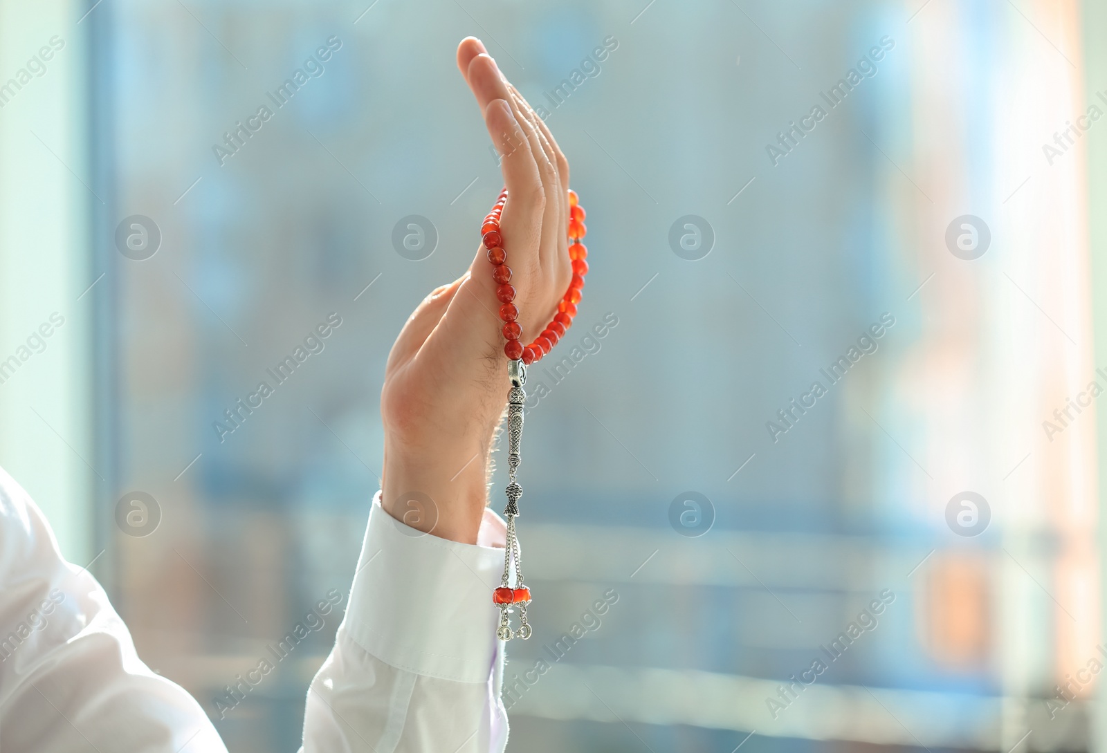 Photo of Muslim man with misbaha praying indoors, closeup. Space for text