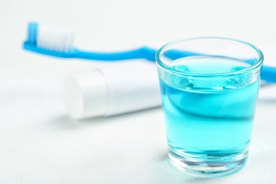 Photo of Glass with mouthwash on light background. Teeth care