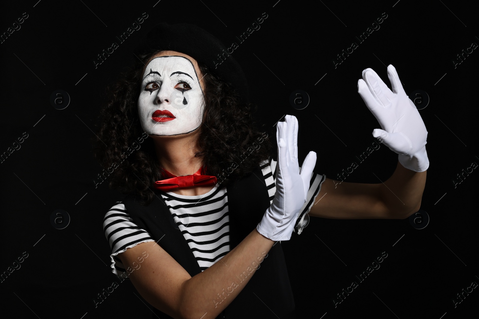 Photo of Young woman in mime costume posing on black background
