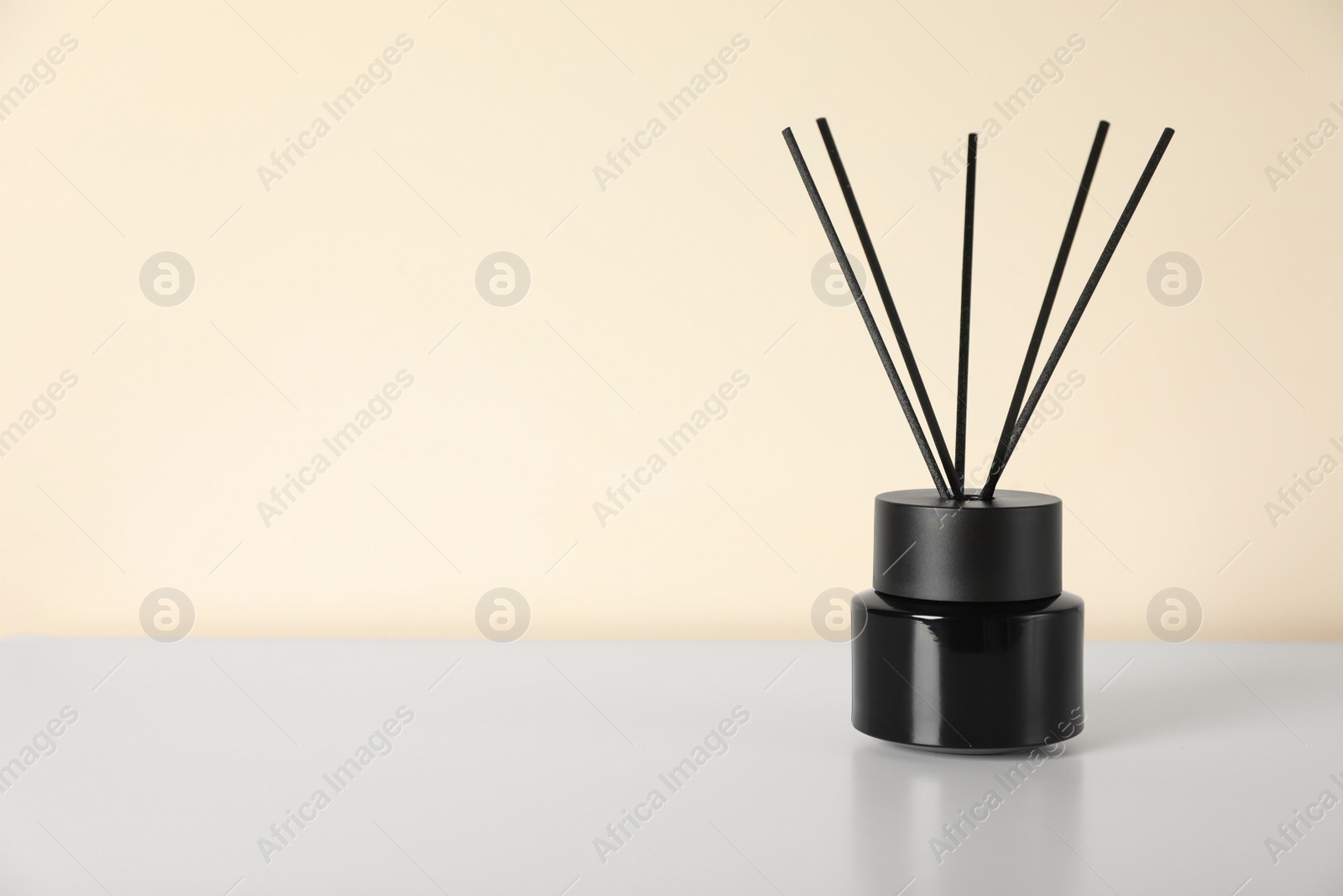 Photo of Aromatic reed air freshener on white table indoors. Space for text