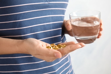 Photo of Woman with fish oil pills and glass of water, closeup