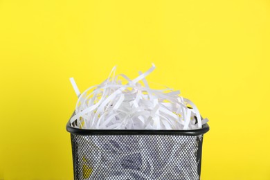 Photo of Trash bin with shredded paper strips on yellow background