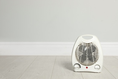 Modern electric fan heater on floor in room, space for text