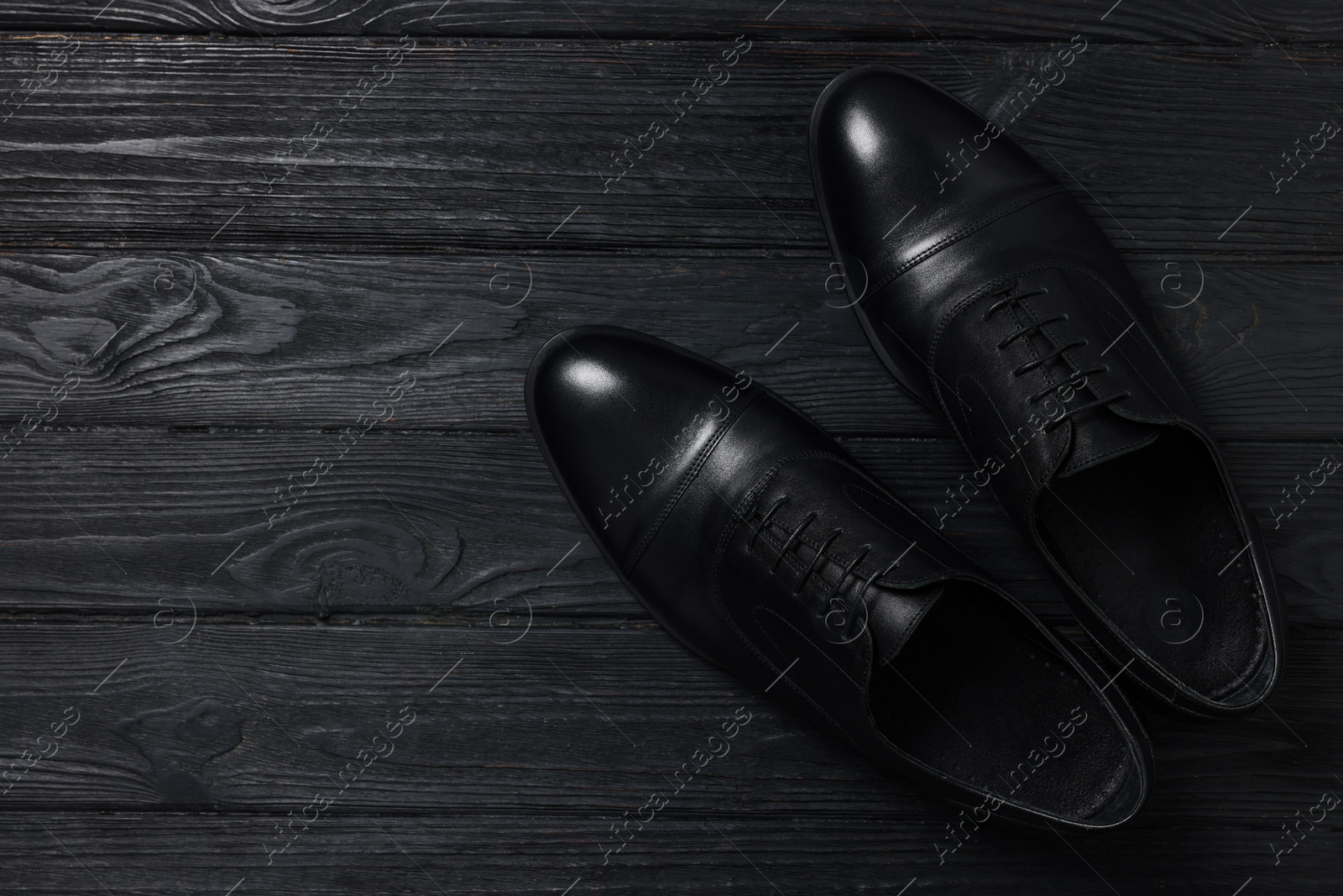 Photo of Pair of leather men shoes on black wooden background, top view. Space for text