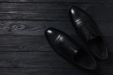 Photo of Pair of leather men shoes on black wooden background, top view. Space for text