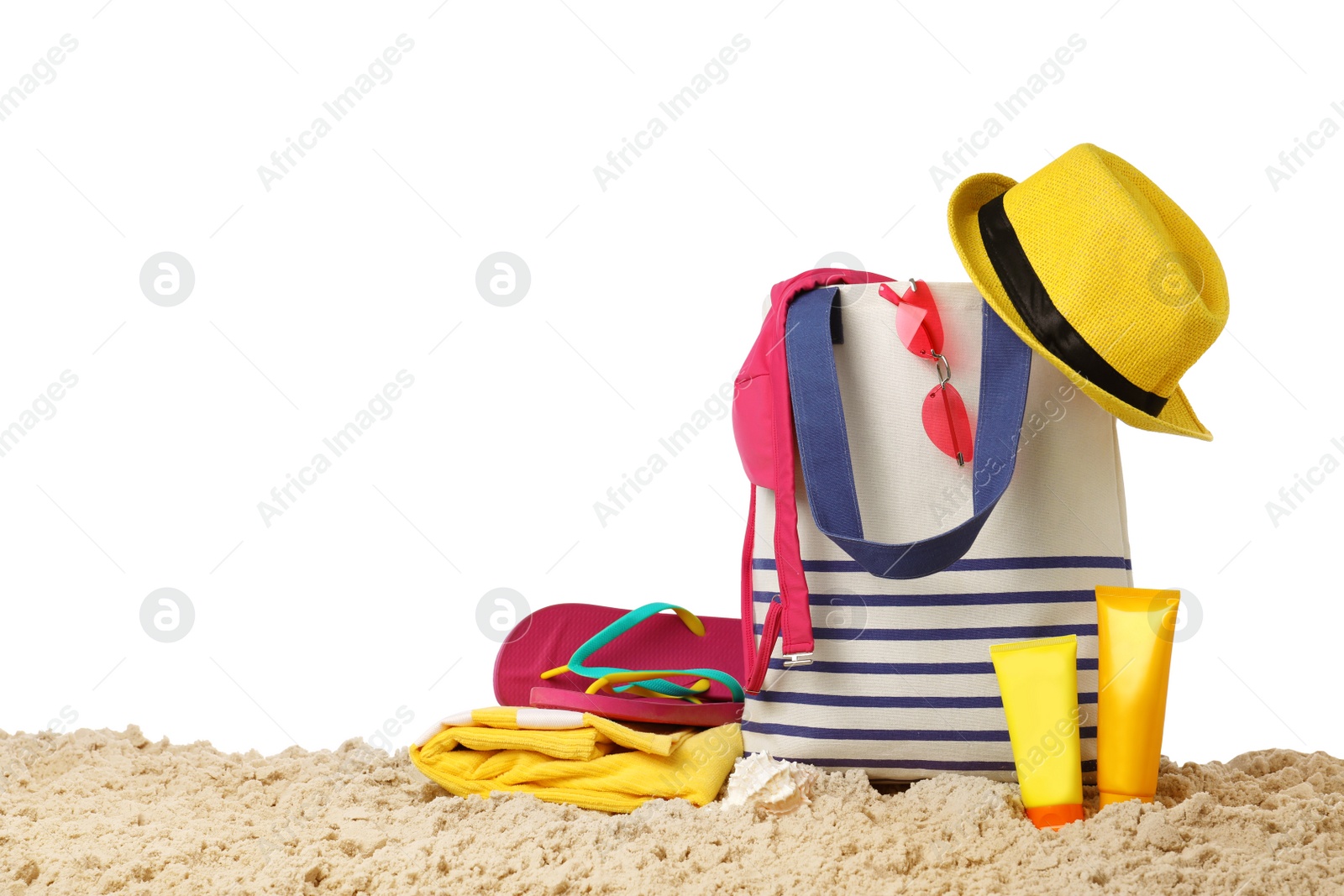 Photo of Stylish bag with beach accessories on sand against white background