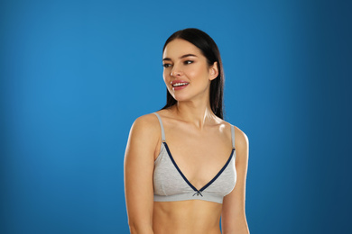 Photo of Beautiful young woman in grey sportive underwear on blue background