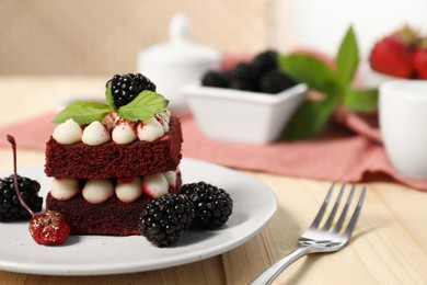 Piece of delicious red velvet cake with fresh berries served on wooden table, closeup. Space for text