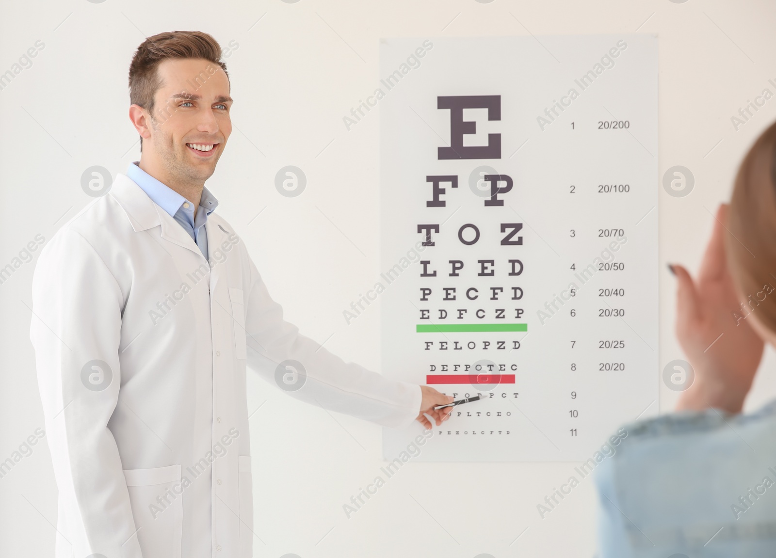 Photo of Young ophthalmologist doing eye exam with his patient indoors