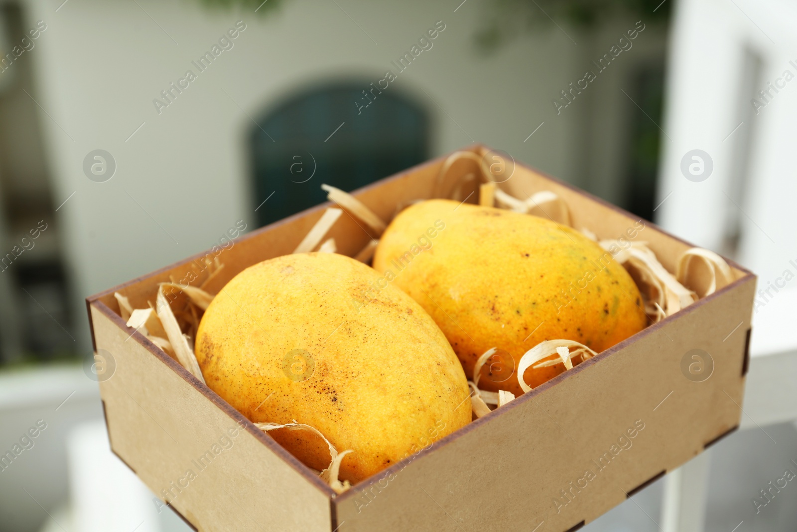 Photo of Delicious ripe yellow mangoes in wooden box outdoors