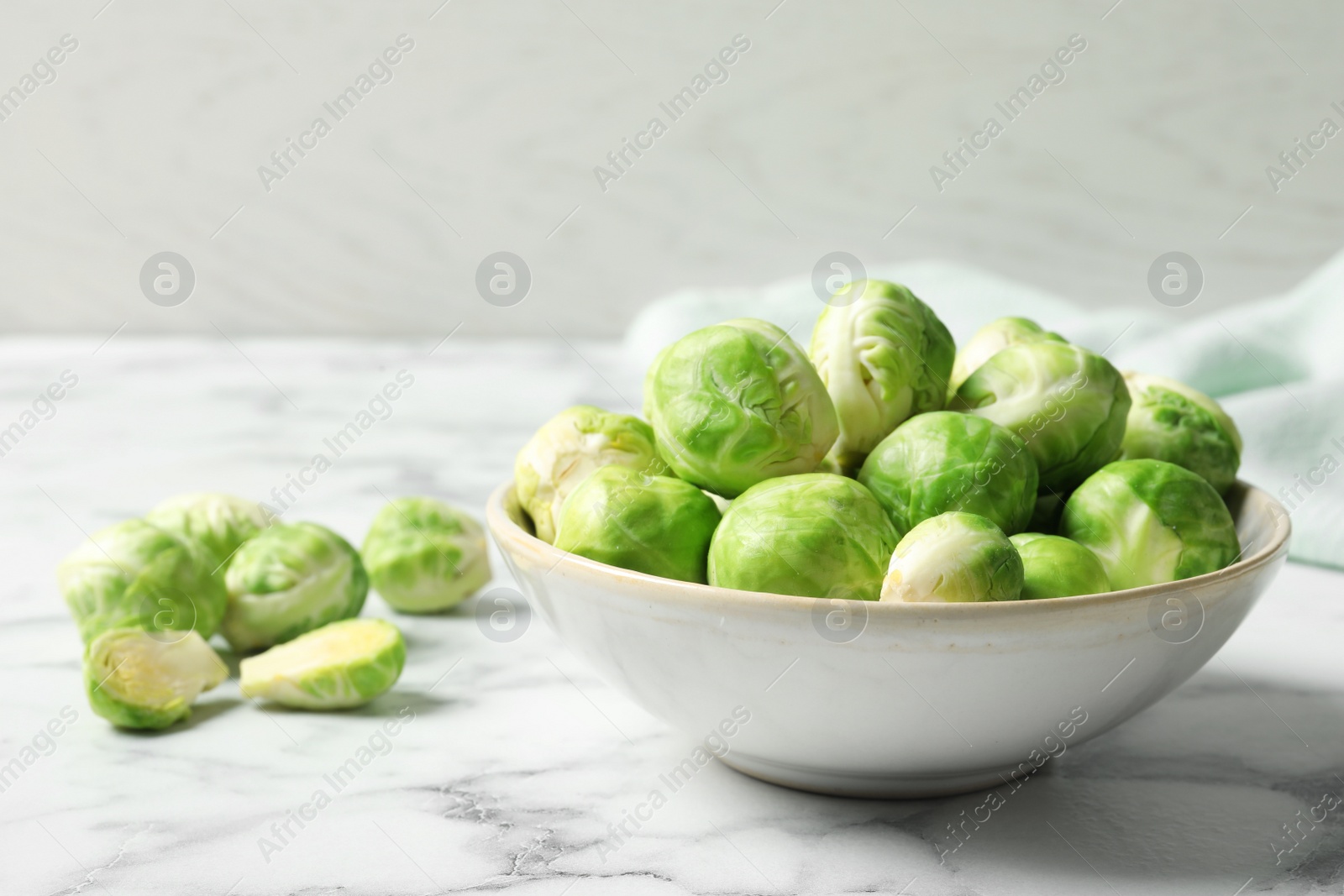 Photo of Bowl with fresh Brussels sprouts on marble table. Space for text