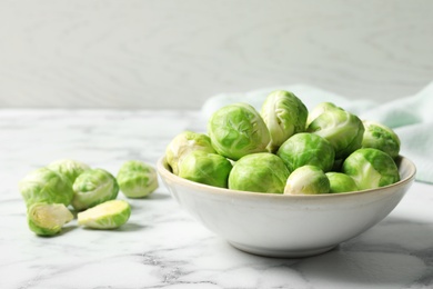 Bowl with fresh Brussels sprouts on marble table. Space for text