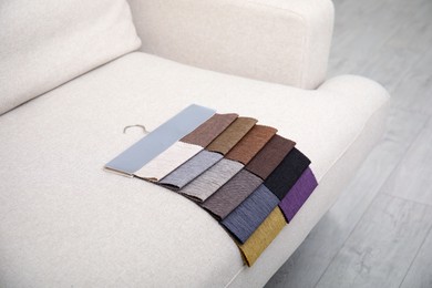 Photo of Catalog of colorful fabric samples on beige sofa indoors