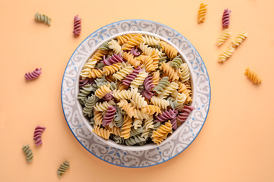 Photo of Colorful fusilli pasta on light orange background, flat lay