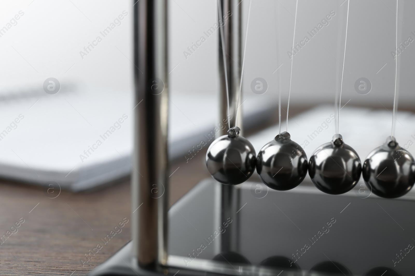 Photo of Newton's cradle on wooden table, closeup. Physics law of energy conservation