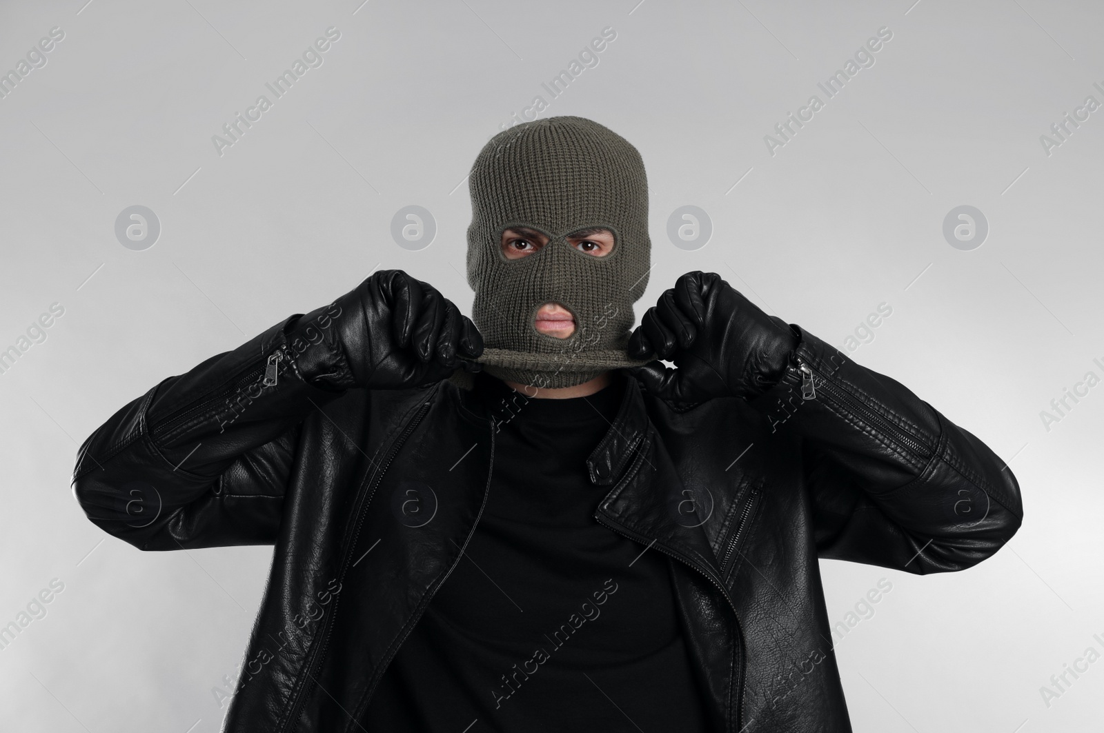 Photo of Man wearing knitted balaclava on light grey background