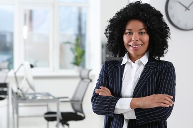 Smiling young businesswoman in modern office. Space for text