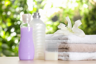 Soft bath towels and laundry detergents on table against blurred background