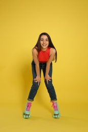 Young woman with roller skates on color background