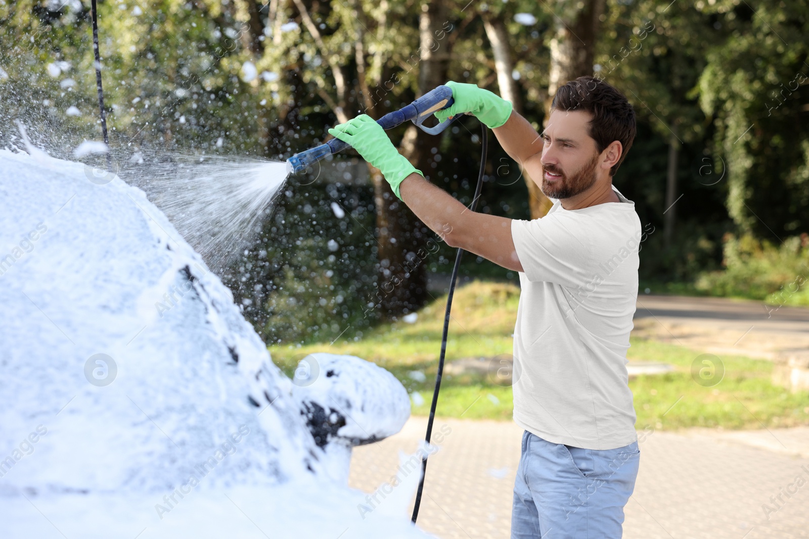 Photo of Man covering automobile with foam at outdoor car wash