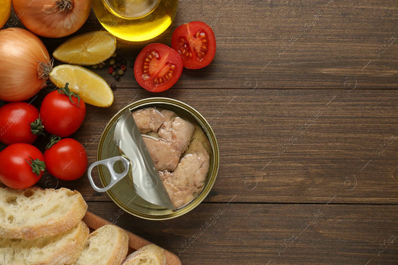 Photo of Flat lay composition with tin can of tasty cod liver and different products on wooden table. Space for text