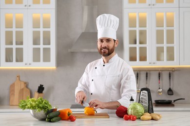 Chef cutting bell pepper at marble table in kitchen