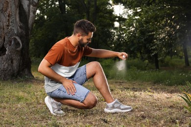 Man applying insect repellent on leg in park. Tick bites prevention
