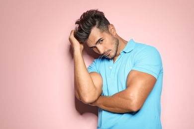 Young man with trendy hairstyle posing on color background