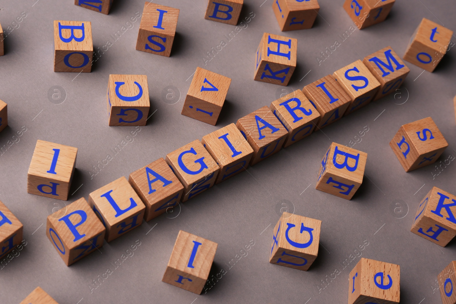 Photo of Wooden cubes with word Plagiarism on grey background