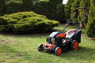 Modern lawn mower on green grass in garden