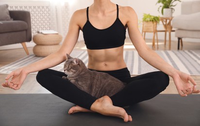 Photo of Woman with cat practicing yoga at home, closeup