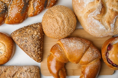 Photo of Fresh breads and pastries on white table, flat lay