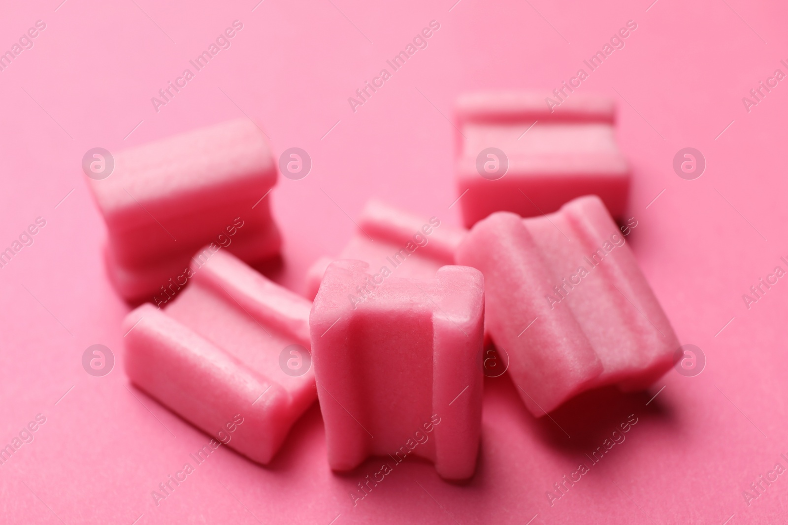 Photo of Tasty chewing gums on pink background, closeup